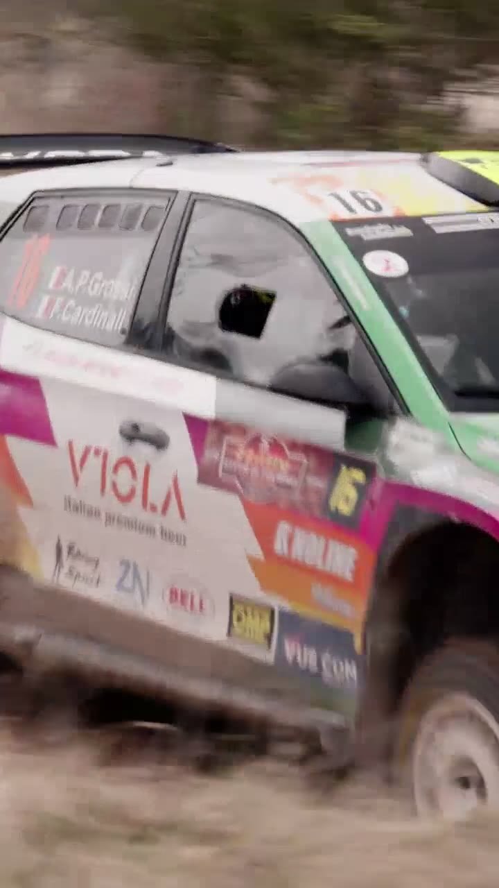 Pilota in tuta da rally davanti alla vettura